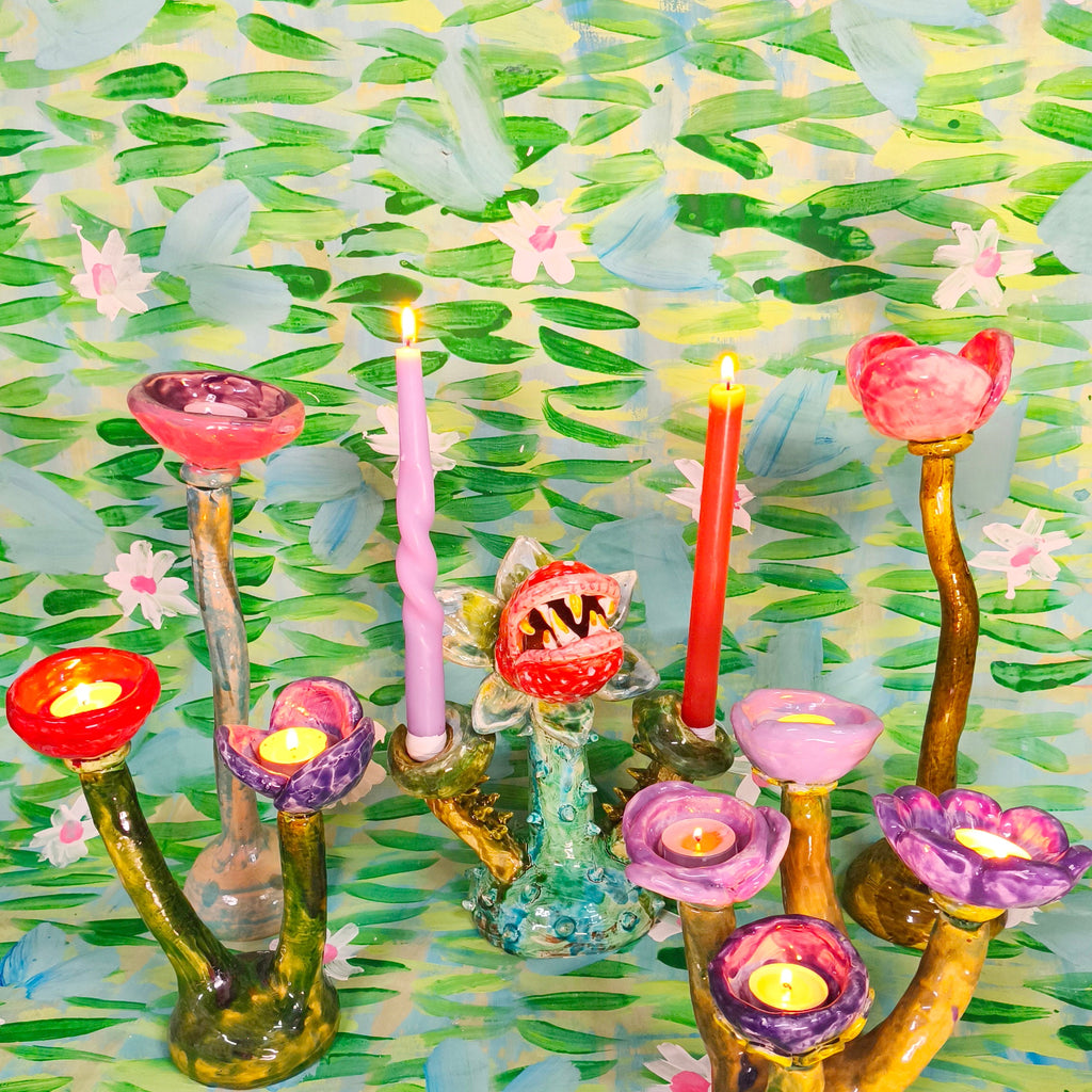 Colorful floral-patterned candle holder with lit candles against a floral background