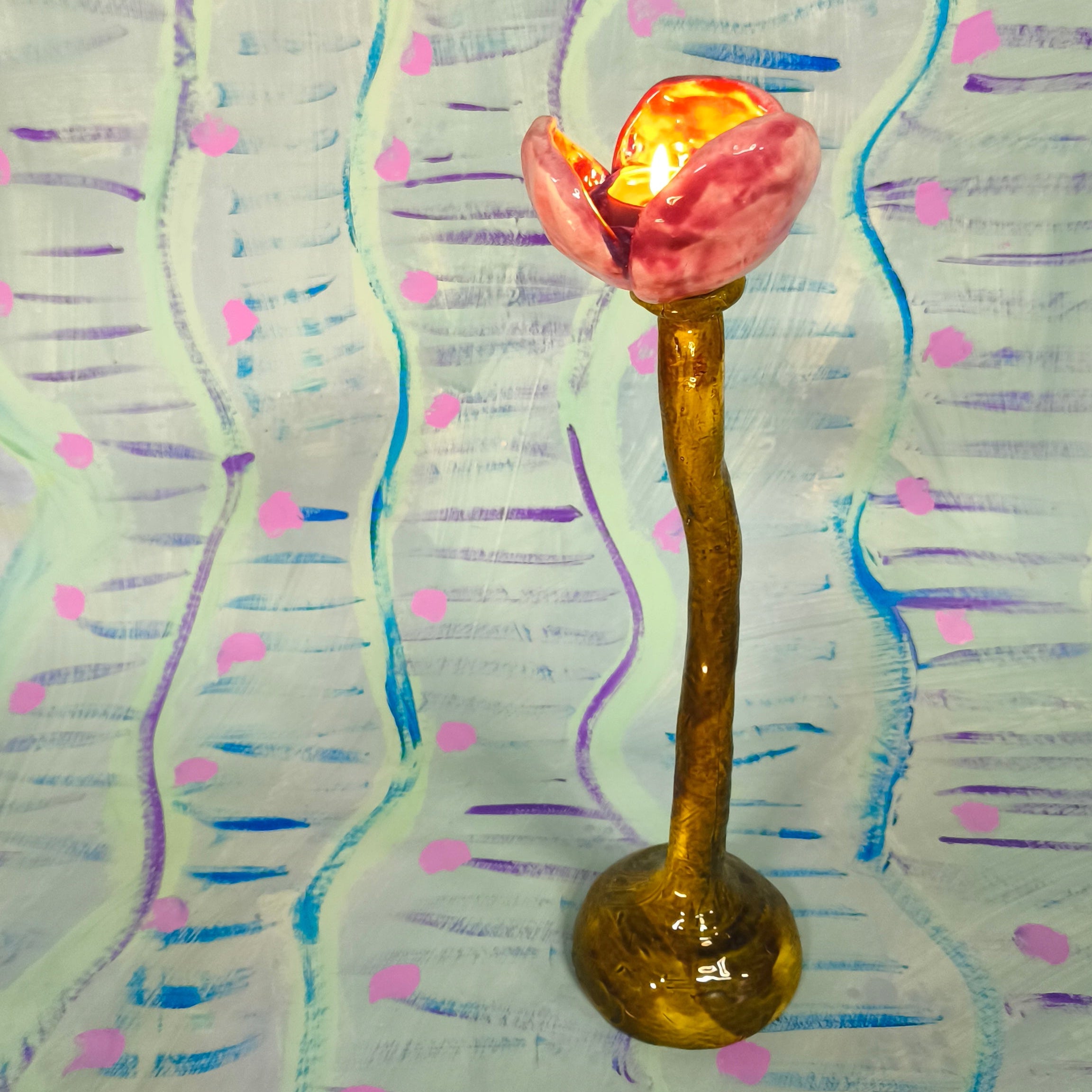 Decorative item with a pink flower and gold base on a colorful abstract background